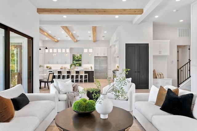 living room featuring beamed ceiling and light hardwood / wood-style floors