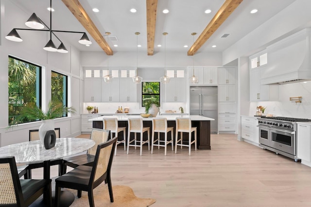 dining area featuring light hardwood / wood-style flooring, beamed ceiling, and a wealth of natural light