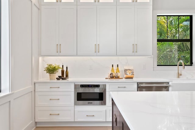 kitchen with tasteful backsplash, appliances with stainless steel finishes, sink, and white cabinetry