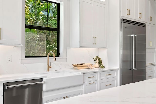 kitchen with light stone countertops, stainless steel appliances, plenty of natural light, and white cabinetry