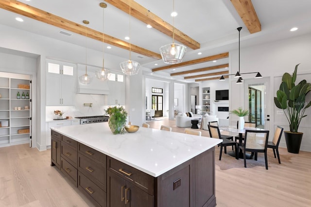 kitchen with beam ceiling, pendant lighting, and light hardwood / wood-style floors