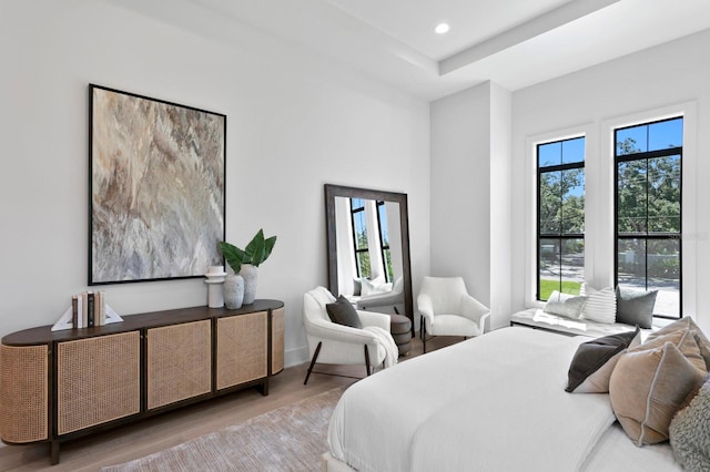 bedroom featuring hardwood / wood-style floors, a tray ceiling, and multiple windows