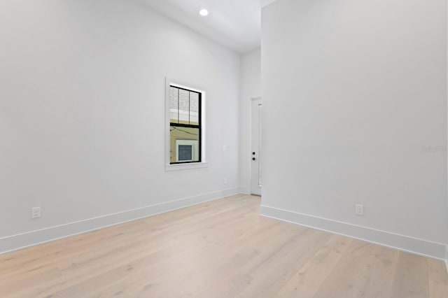 empty room featuring a high ceiling and light hardwood / wood-style floors