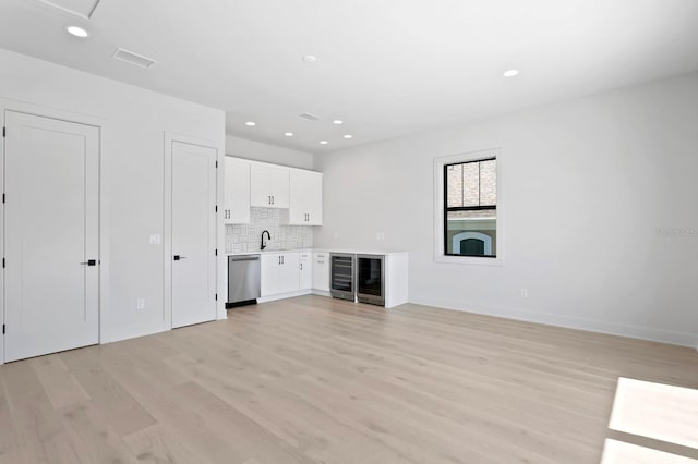 unfurnished living room featuring light hardwood / wood-style flooring, wine cooler, and sink