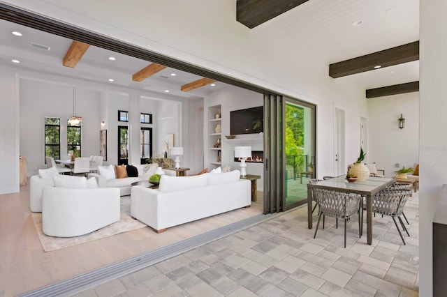 living room featuring built in shelves, beam ceiling, light tile patterned floors, and a wealth of natural light