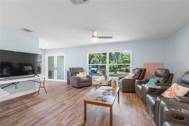 living room with ceiling fan, a textured ceiling, french doors, and wood-type flooring