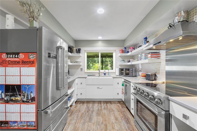 kitchen featuring sink, decorative backsplash, light hardwood / wood-style floors, white cabinetry, and premium appliances