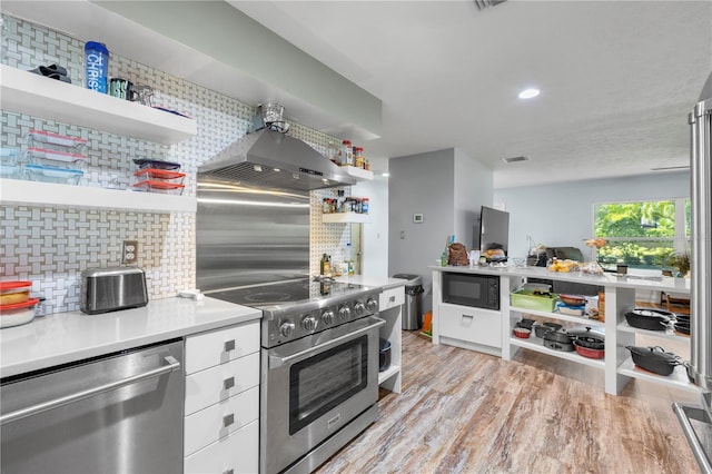 kitchen featuring light hardwood / wood-style flooring, backsplash, wall chimney exhaust hood, white cabinets, and stainless steel appliances