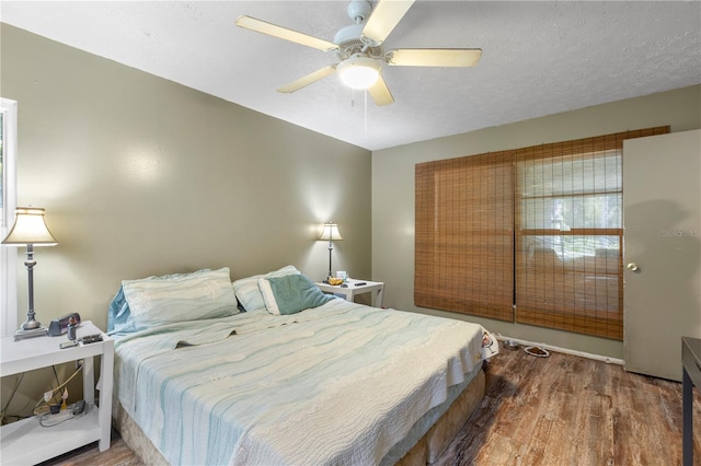 bedroom with ceiling fan, a textured ceiling, and wood-type flooring