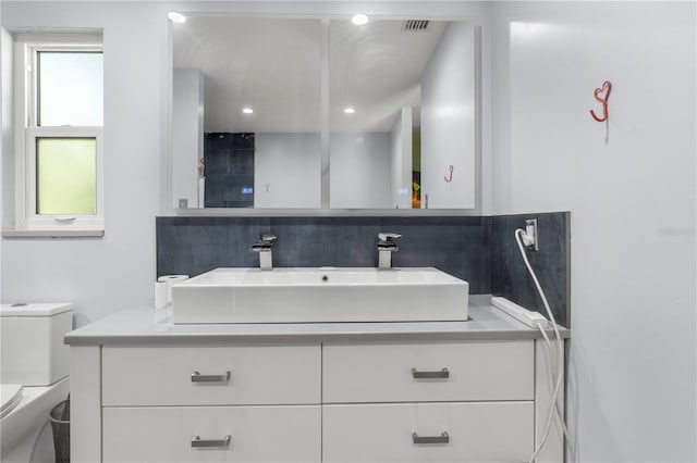 bathroom featuring plenty of natural light, toilet, tasteful backsplash, and vanity