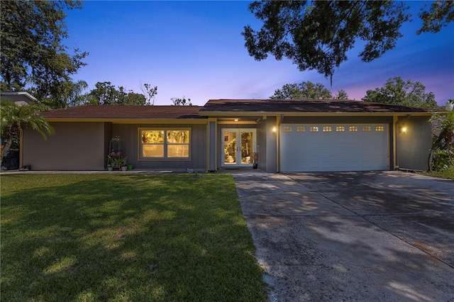 ranch-style home with a garage and a lawn