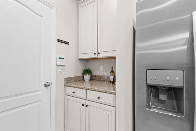 kitchen with light stone countertops, stainless steel fridge with ice dispenser, and white cabinets