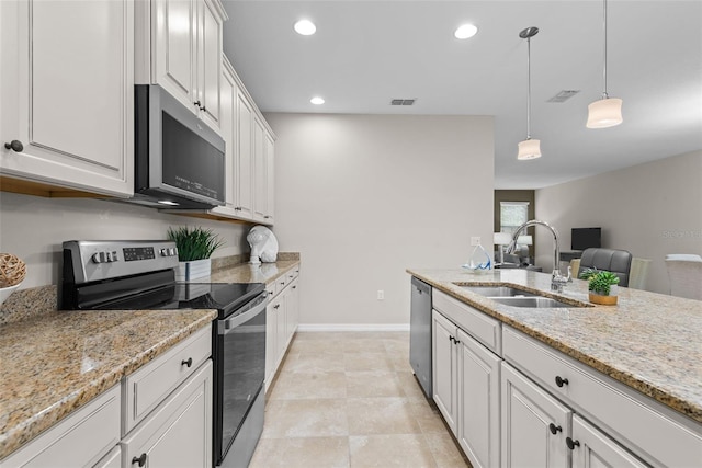 kitchen with stainless steel appliances, light stone countertops, pendant lighting, sink, and white cabinetry