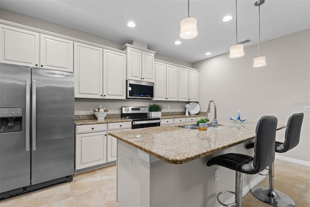 kitchen featuring sink, light stone counters, appliances with stainless steel finishes, an island with sink, and white cabinets