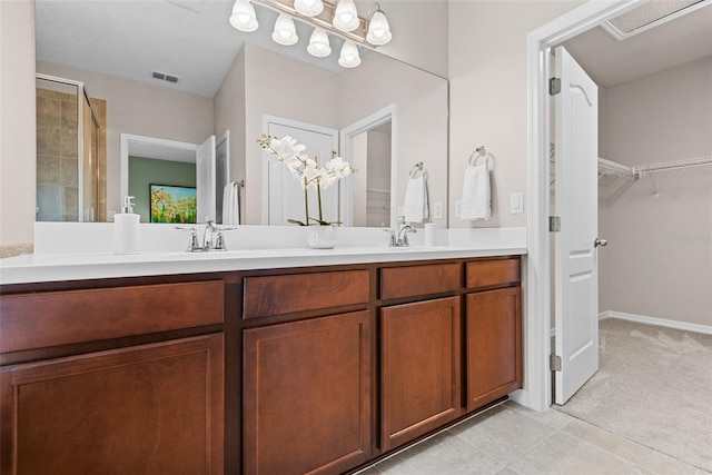 bathroom featuring a shower with shower door, vanity, and tile patterned flooring