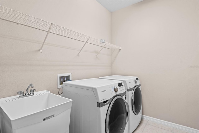 laundry room featuring light tile patterned floors, sink, and separate washer and dryer