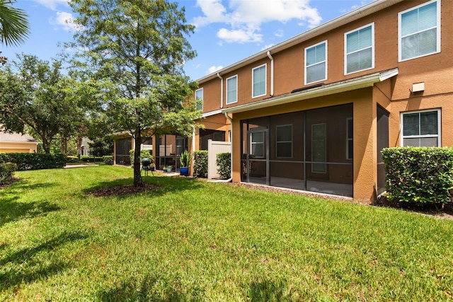 rear view of property with a lawn and a sunroom