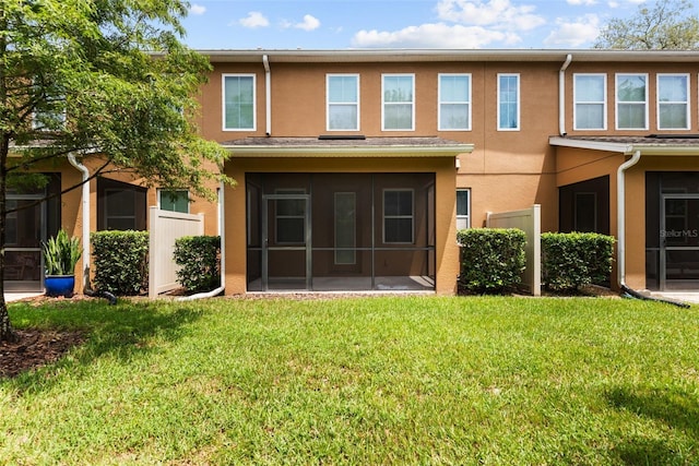 rear view of house featuring a sunroom and a yard