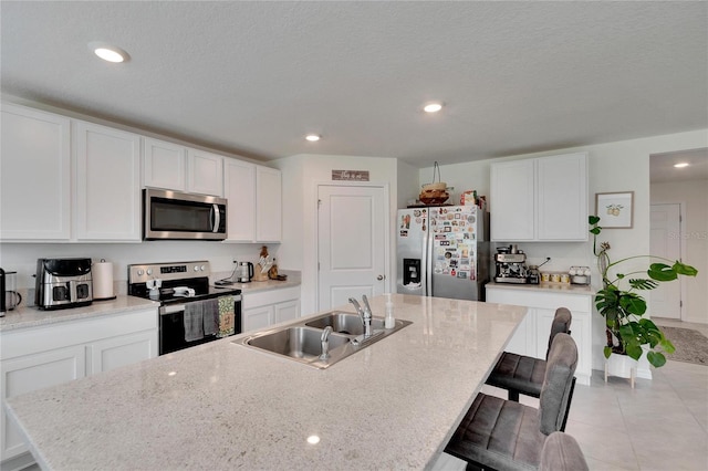 kitchen featuring white cabinetry, appliances with stainless steel finishes, sink, and a center island with sink