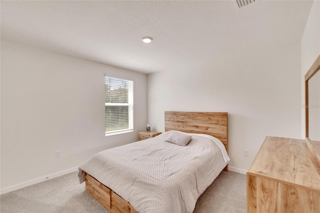 bedroom featuring light colored carpet and a textured ceiling