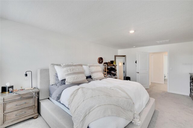 bedroom with a textured ceiling and light colored carpet