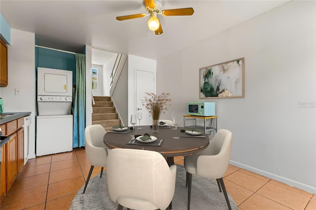 dining space featuring stacked washer and clothes dryer, ceiling fan, and light tile patterned floors