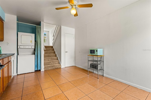 kitchen featuring white appliances, light tile patterned flooring, stacked washer and clothes dryer, and ceiling fan