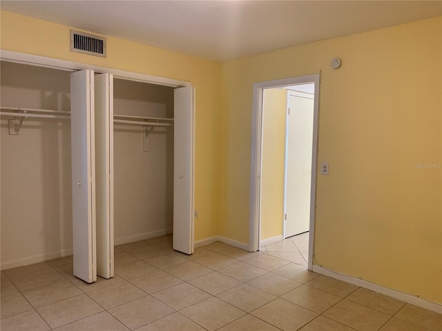 unfurnished bedroom featuring light tile patterned flooring and two closets