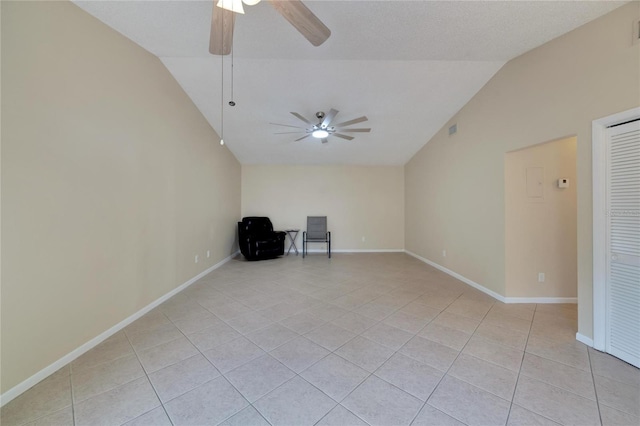 unfurnished room with ceiling fan, vaulted ceiling, baseboards, and light tile patterned floors