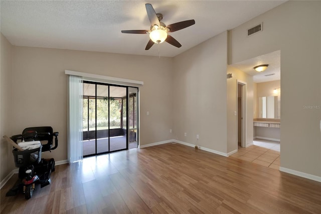 spare room featuring light wood-type flooring, visible vents, lofted ceiling, and baseboards