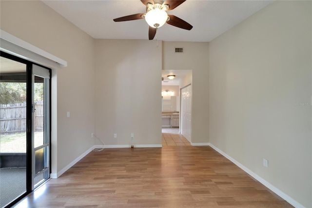 empty room with ceiling fan, light wood finished floors, visible vents, and baseboards