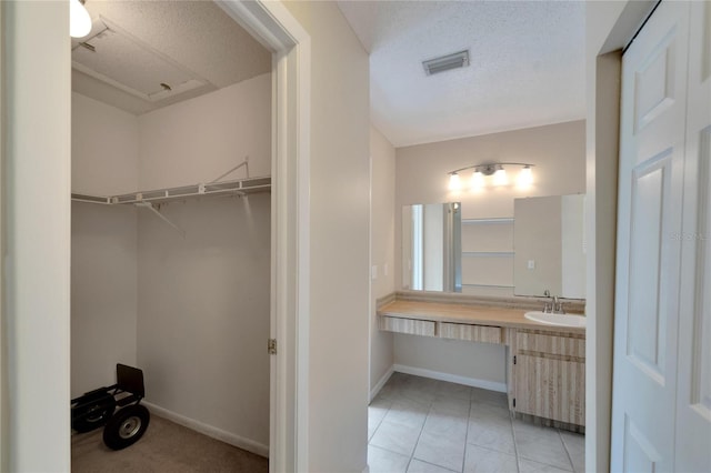 bathroom featuring baseboards, visible vents, a textured ceiling, and vanity