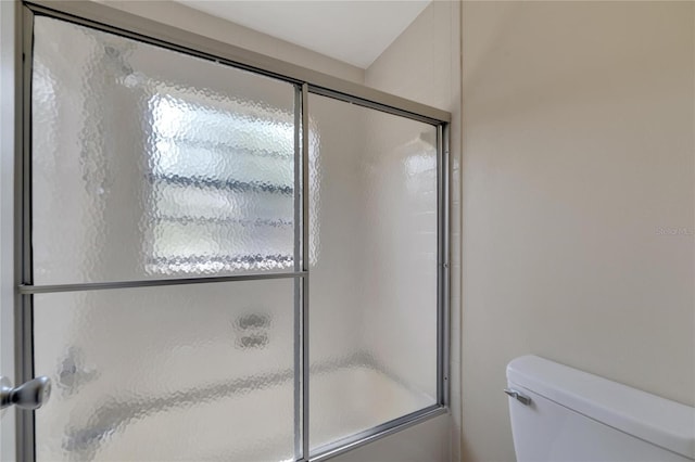 bathroom with toilet and bath / shower combo with glass door