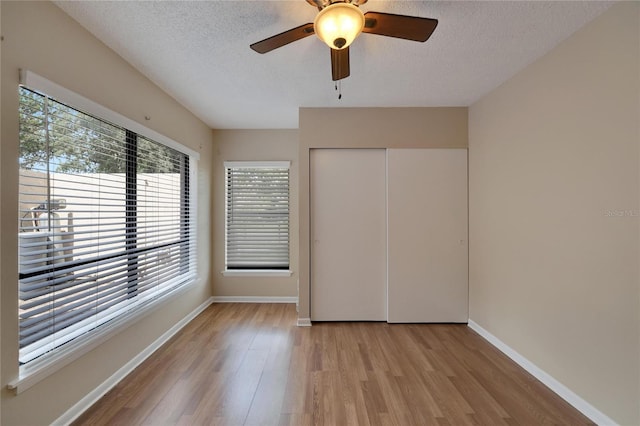 unfurnished bedroom with a textured ceiling, a closet, light wood-type flooring, and baseboards