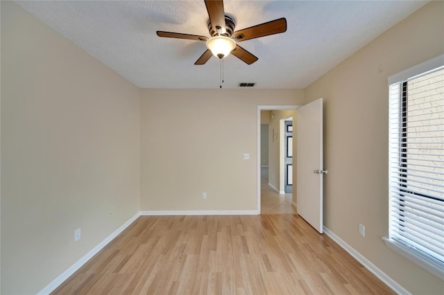 unfurnished room featuring a textured ceiling, ceiling fan, visible vents, baseboards, and light wood-type flooring