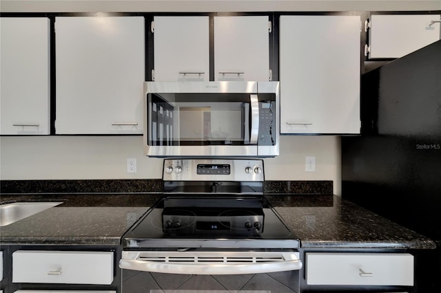 kitchen with appliances with stainless steel finishes, white cabinets, and dark stone countertops