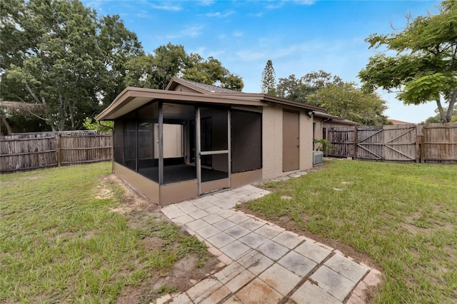 back of property featuring a sunroom, a fenced backyard, a gate, and a yard