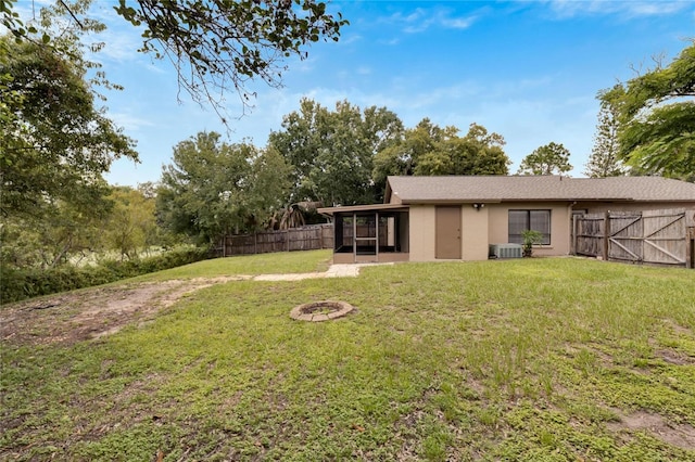 back of house featuring a yard, an outdoor fire pit, fence, and central air condition unit