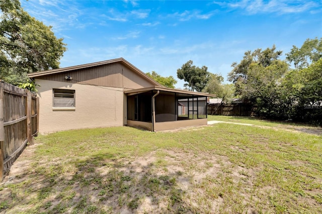 rear view of property with a yard, a fenced backyard, and a sunroom