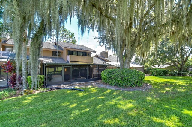 rear view of house with a sunroom and a yard