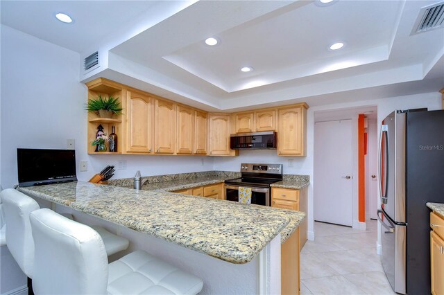 kitchen featuring light tile patterned flooring, stainless steel appliances, a raised ceiling, and light stone countertops