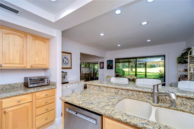 kitchen featuring light brown cabinetry, sink, dishwasher, and light stone counters