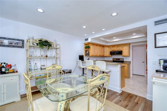 dining space featuring light wood-type flooring and a tray ceiling