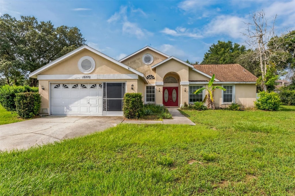 ranch-style home with concrete driveway, an attached garage, a front lawn, and stucco siding