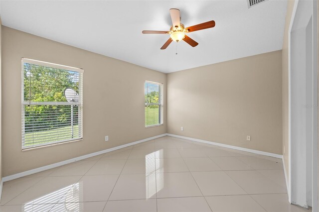 tiled spare room featuring a healthy amount of sunlight and ceiling fan