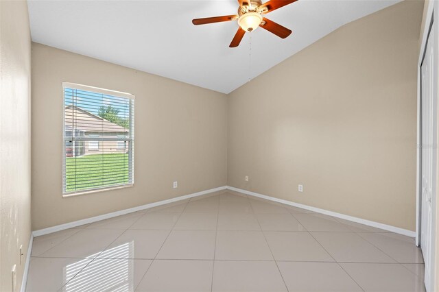 tiled empty room featuring vaulted ceiling and ceiling fan