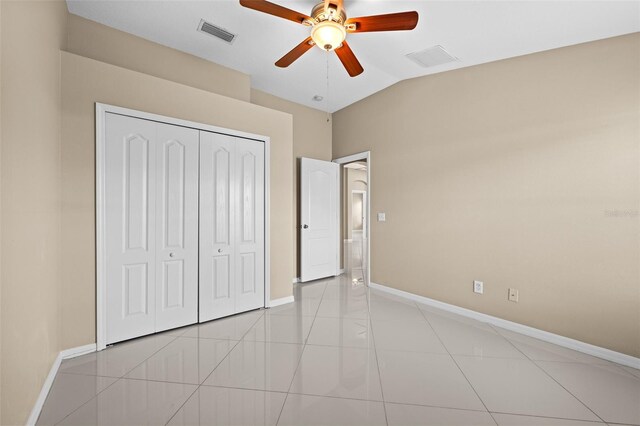 unfurnished bedroom featuring a closet, light tile patterned floors, vaulted ceiling, and ceiling fan