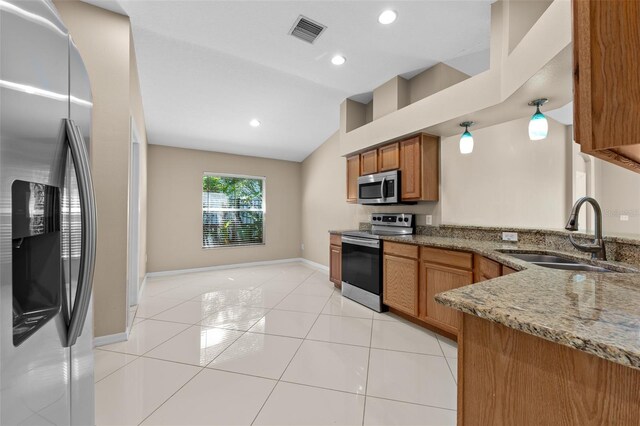 kitchen featuring sink, dark stone counters, stainless steel appliances, and light tile patterned floors