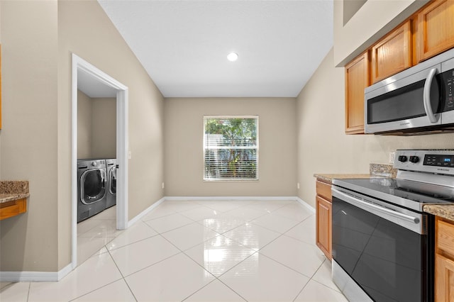 kitchen featuring light tile patterned floors, independent washer and dryer, light stone counters, and stainless steel appliances