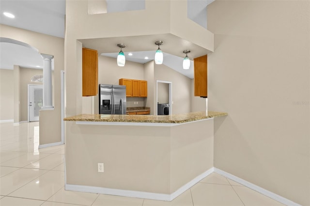 kitchen with kitchen peninsula, lofted ceiling, light tile patterned floors, and stainless steel fridge with ice dispenser